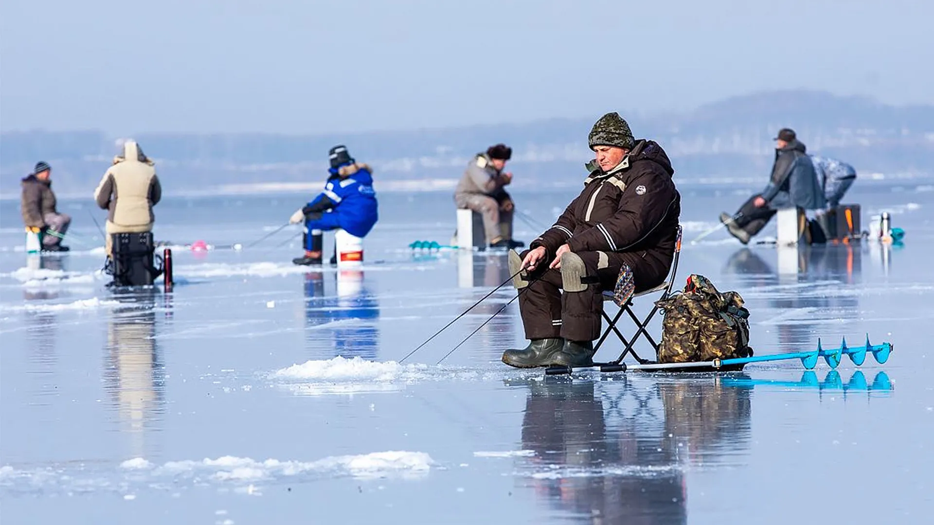 Ice fishing on frozen lake in extreme winter conditions