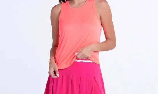Coral sleeveless tennis tank top in lightweight performance fabric over a bright pink pleated skirt