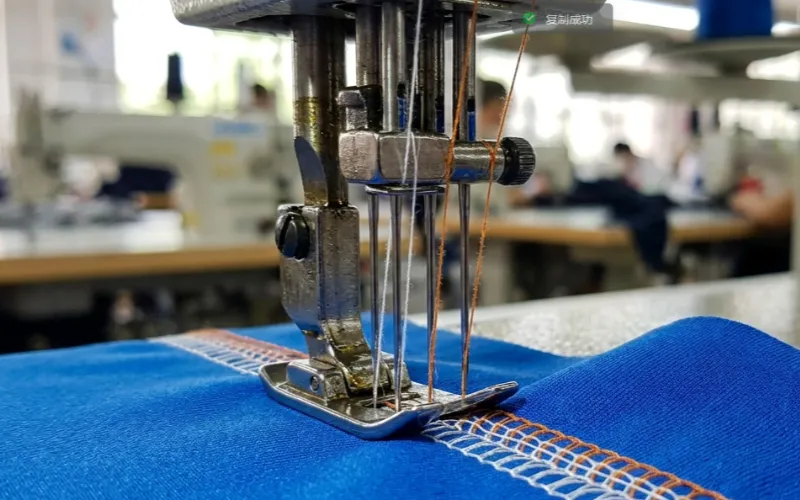 Industrial flat-lock sewing machine stitching high-stretch cycling fabric.